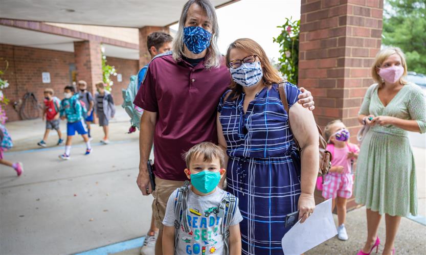 A mother, father and child smile